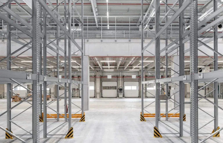 Leeres Lager- und Logistikgebäude mit hohen Metallregalen und hellem Boden der Firma Kraftverkehr Nagel