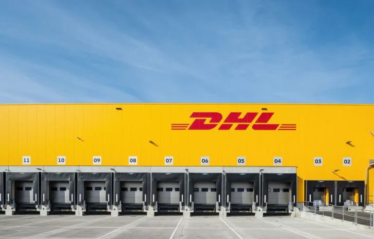 DHL-Logistikzentrum mit Laderampen im Hintergrund vor blauem Himmel