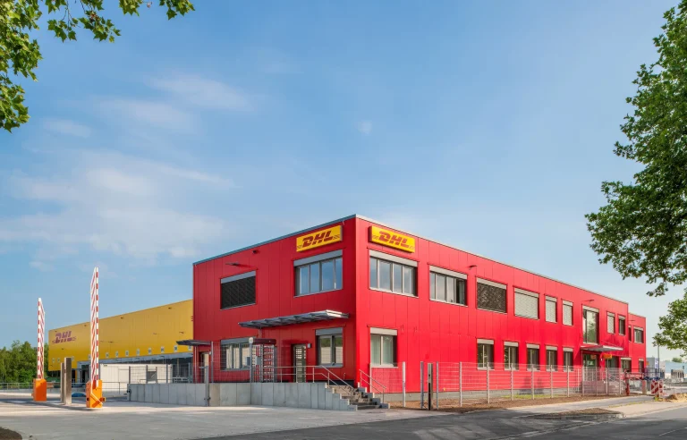 DHL-Logistikzentrum mit Laderampen im Hintergrund vor blauem Himmel