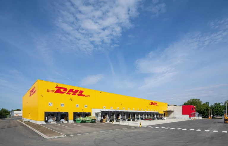 DHL-Logistikzentrum mit DHL-Logo und gelber Fassade mit mehreren Laderampen unter blauem Himmel