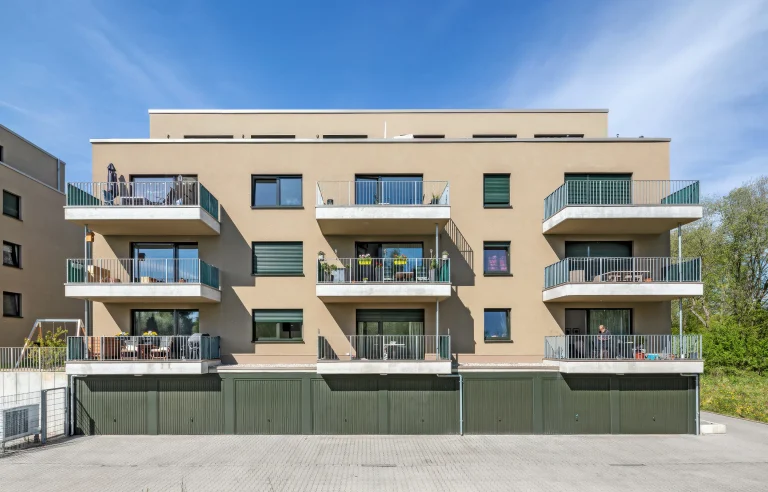 Modernes Mehrfamilienhaus mit Balkonen und Garagen.