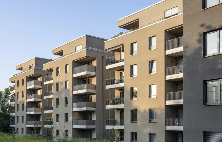 Mehrfamilienhaus mit modernen Balkonen und großen Fenstern bei Tageslicht.